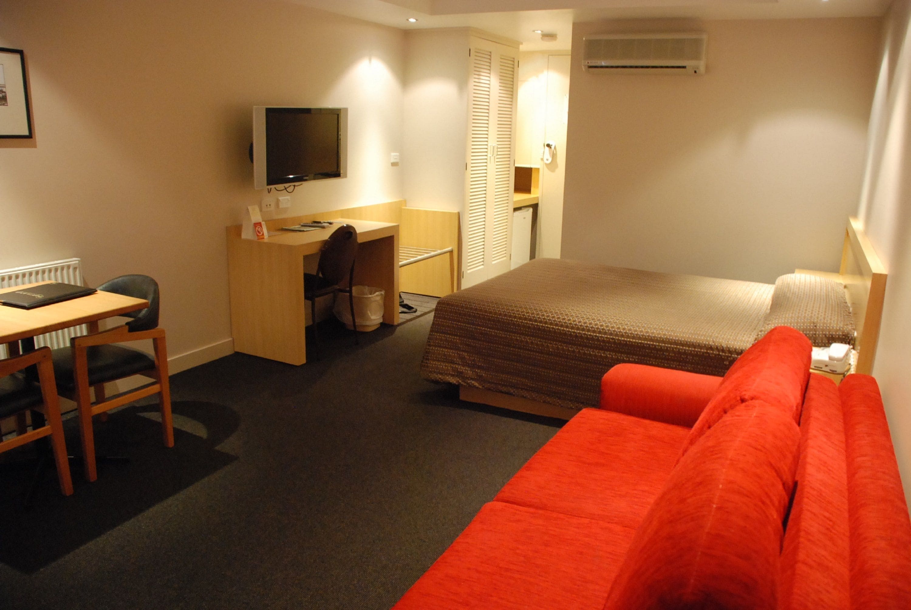 Een hotelkamer met een bed, een bureau met stoel, een televisie en een kledingkast.