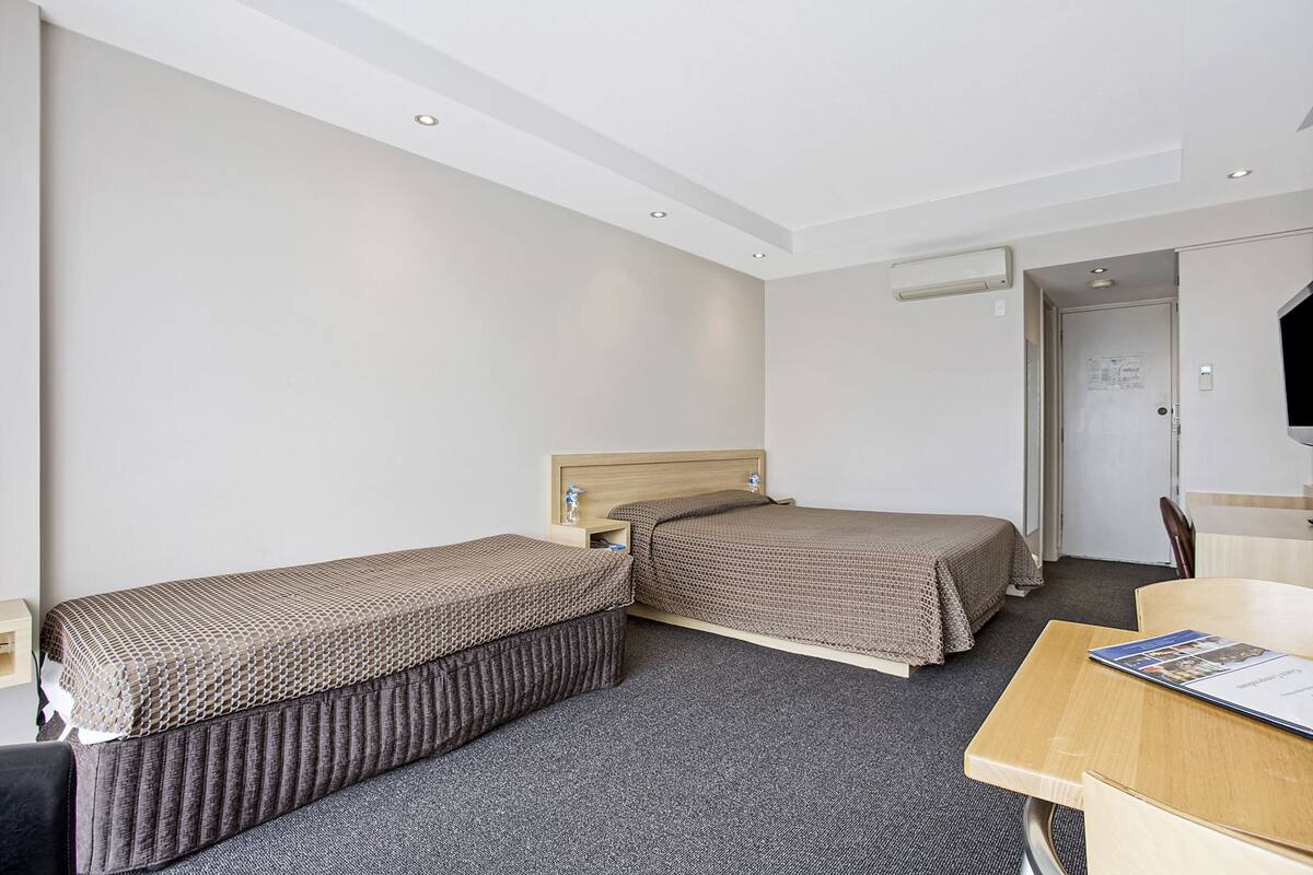 A hotel room with two single beds, a desk, and a chair.