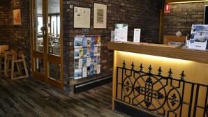 A reception area with a brick wall, a wooden reception desk, and a bulletin board with various notices.