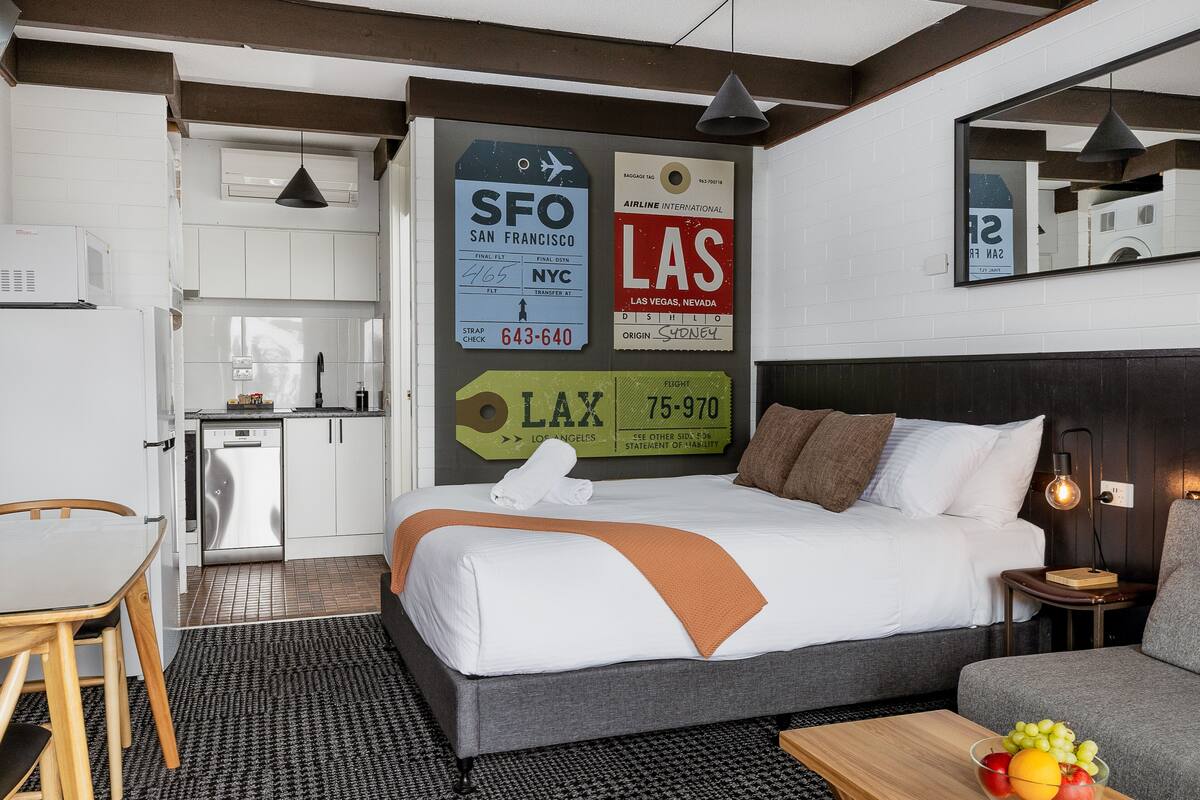 Una habitación de hotel con cama, una mesa de comedor, una zona de cocina y un espejo.