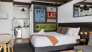 Una habitación de hotel con cama, una mesa de comedor, una zona de cocina y un espejo.