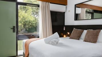 Ein Hotelzimmer mit Bett, einem Fenster mit Vorhängen, einem Spiegel und einer Tür.
