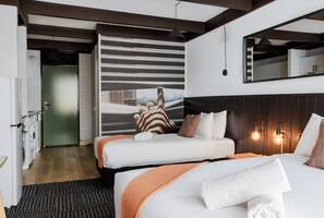 A hotel room with two beds, a large mirror, and a view of the city.