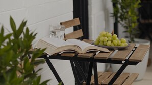 A wooden table with an open book, a glass of water, and a plate of grapes. - m. hotel (Sale)