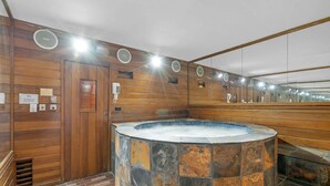 Ein Wellnessbereich mit Stein-Hottub, Holzwänden und einem Spiegel, der den Raum widerspiegelt.