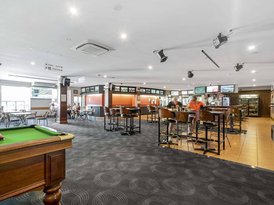 A pool table in a restaurant with multiple seating areas and a buffet.