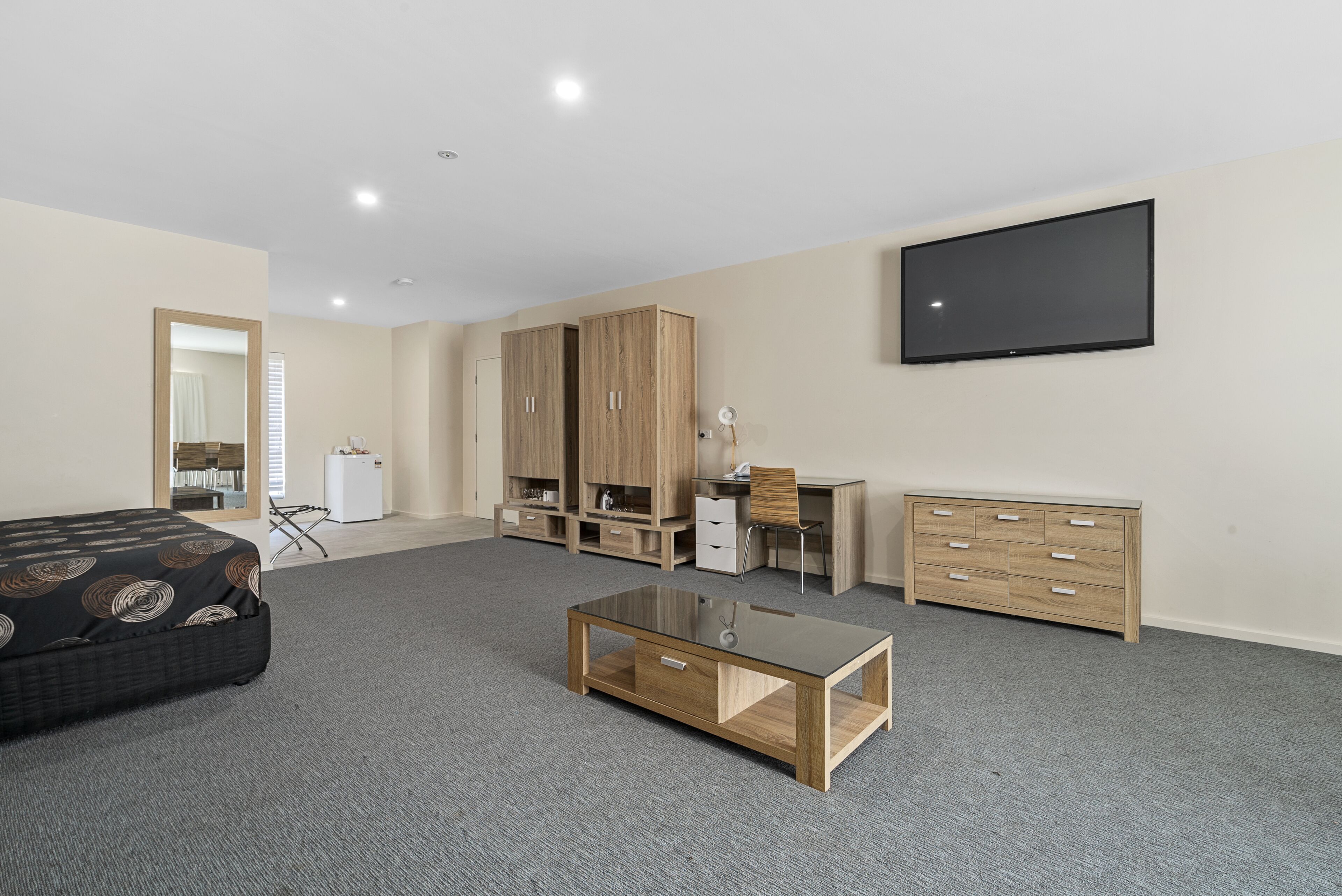 Ein modernes Schlafzimmer mit Bett, Schreibtisch, Fernseher und Einbauschränken.