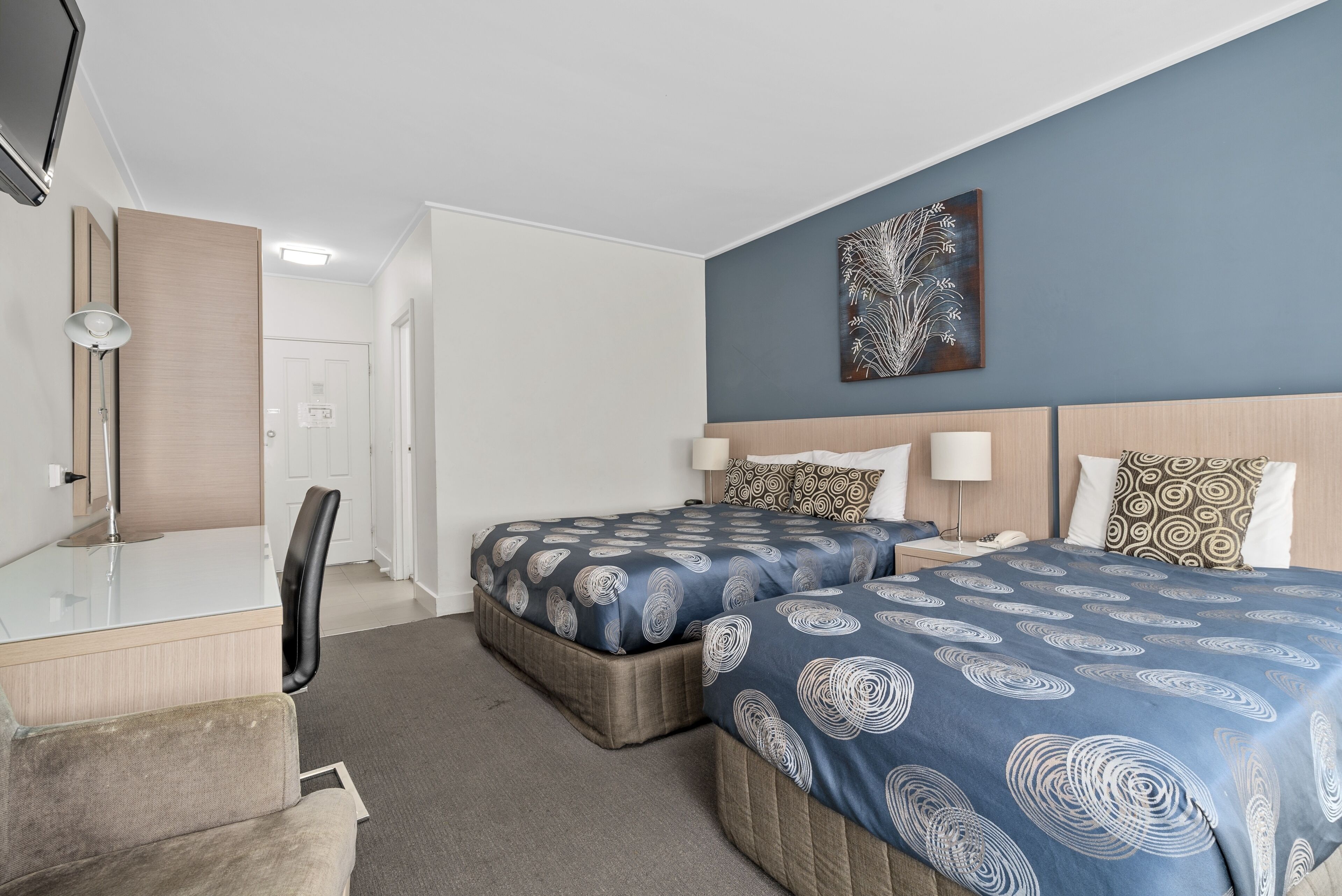 Een hotelkamer met twee bedden, een bureau en een stoel.
