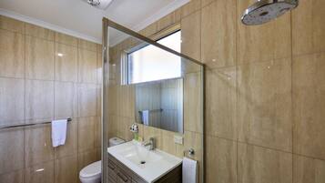 Un bany modern amb una cabina de dutxa de vidre, un lavabo blanc i un vàter.