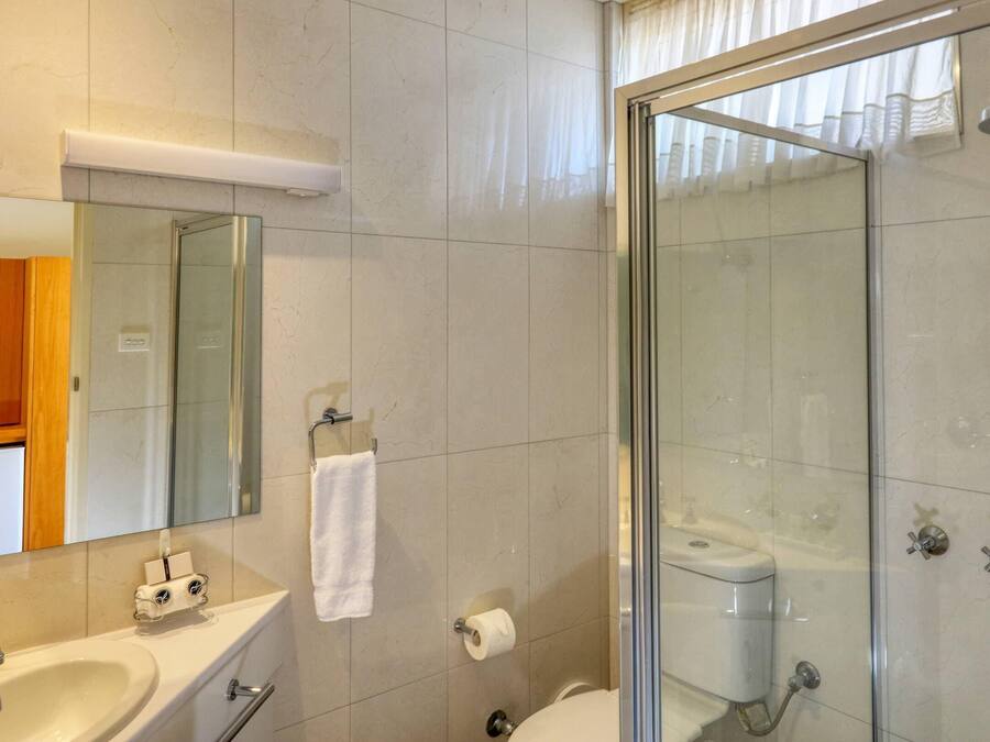 A modern bathroom with a glass-enclosed shower, a sink, a toilet, and a mirror.