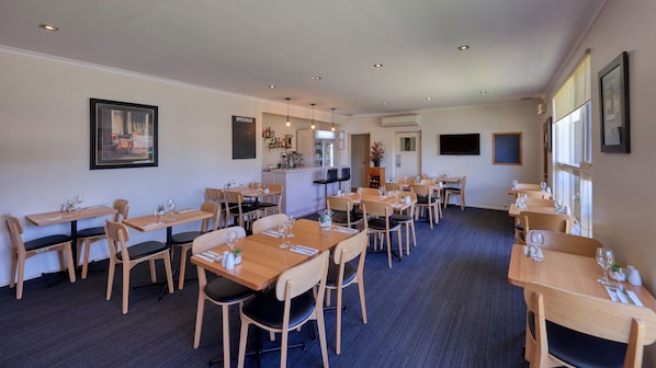 A restaurant with multiple wooden tables and chairs, a bar area, and a television screen on the wall. - Quality Inn Swan Hill (Swan Hill)