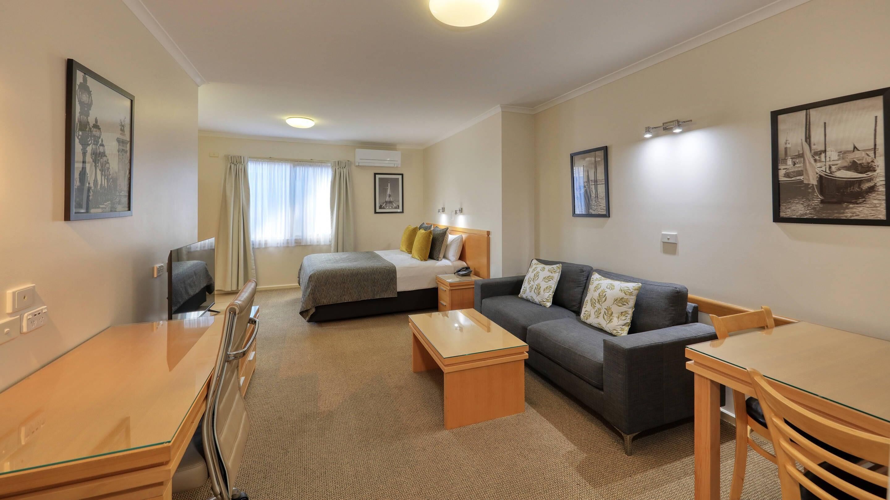 A hotel room with a bed, a sofa, a desk, and a television.