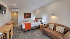 A hotel room with a bed, a sofa, a desk, and a chair. - Quality Inn Swan Hill (Swan Hill)