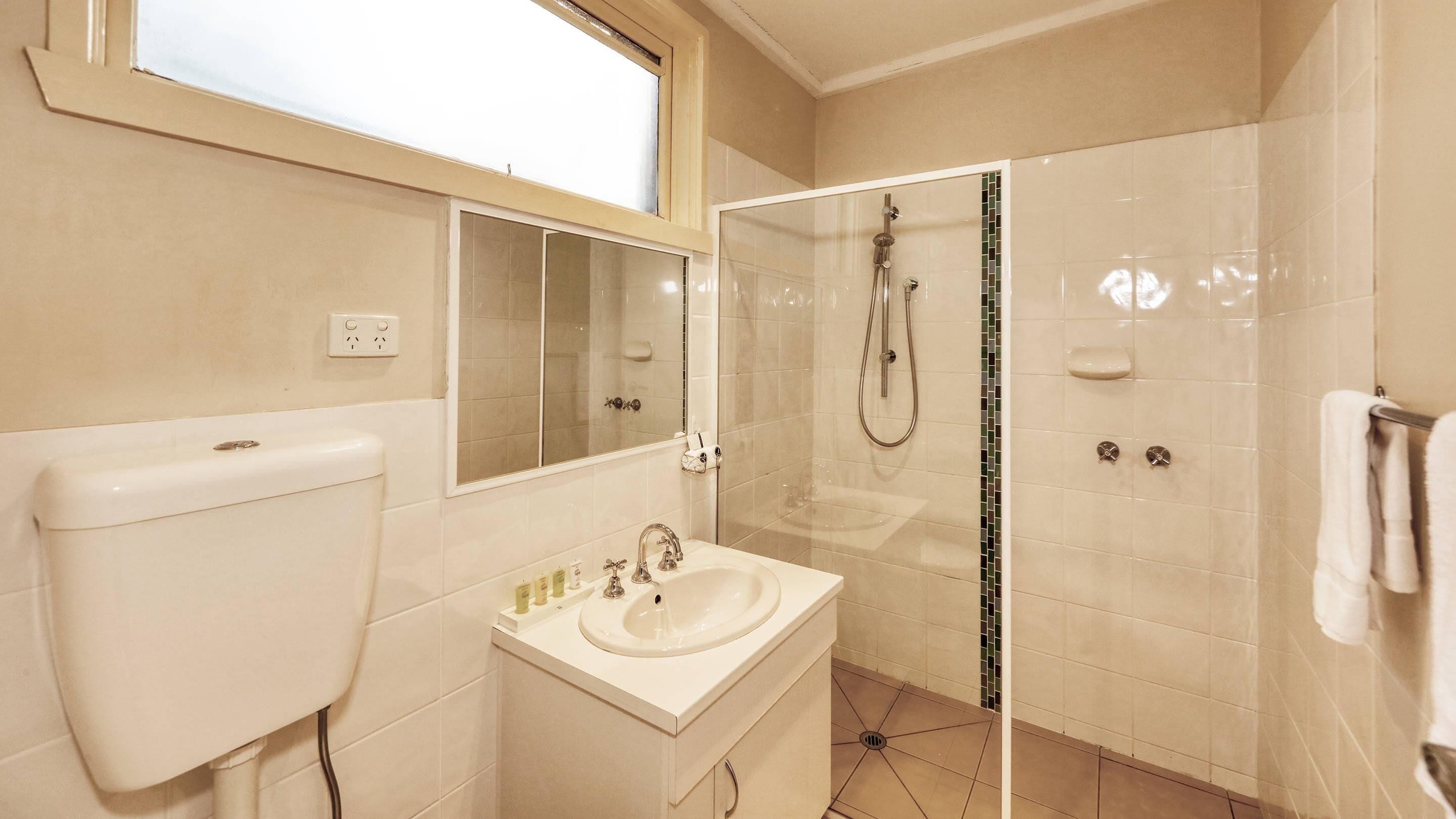 Une salle de bain avec des toilettes, un lavabo et une douche.