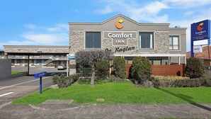 Un hotel Comfort Inn con fachada de piedra, cielo despejado y césped bien cuidado.