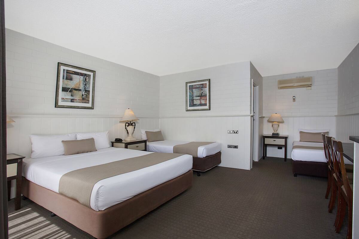 A hotel room with a large bed, a smaller bed, a desk, and a chair.