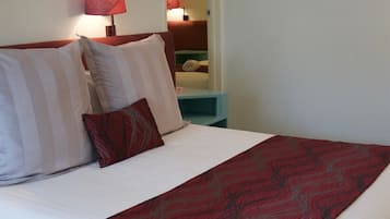 Una cama bien hecha con almohadillas a rayas y una colcha estampada en rojo.