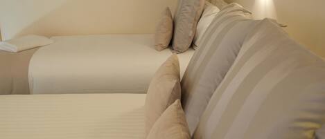 Una habitación de hotel con dos camas, cada una con una almohada a rayas y una manta blanca.