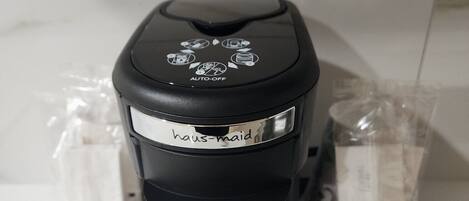 Una cafetera negra con una etiqueta que dice "haus-maid" sobre una encimera de cocina.