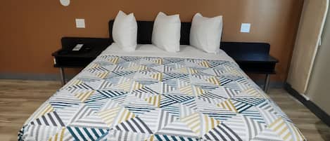 Una habitación de hotel con cama, mesita de noche y toma de corriente.