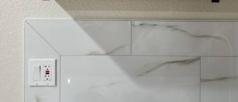 Una cocina con una estufa blanca, dos hornillas negras, un salpicadero blanco y un estante negro sobre la estufa.