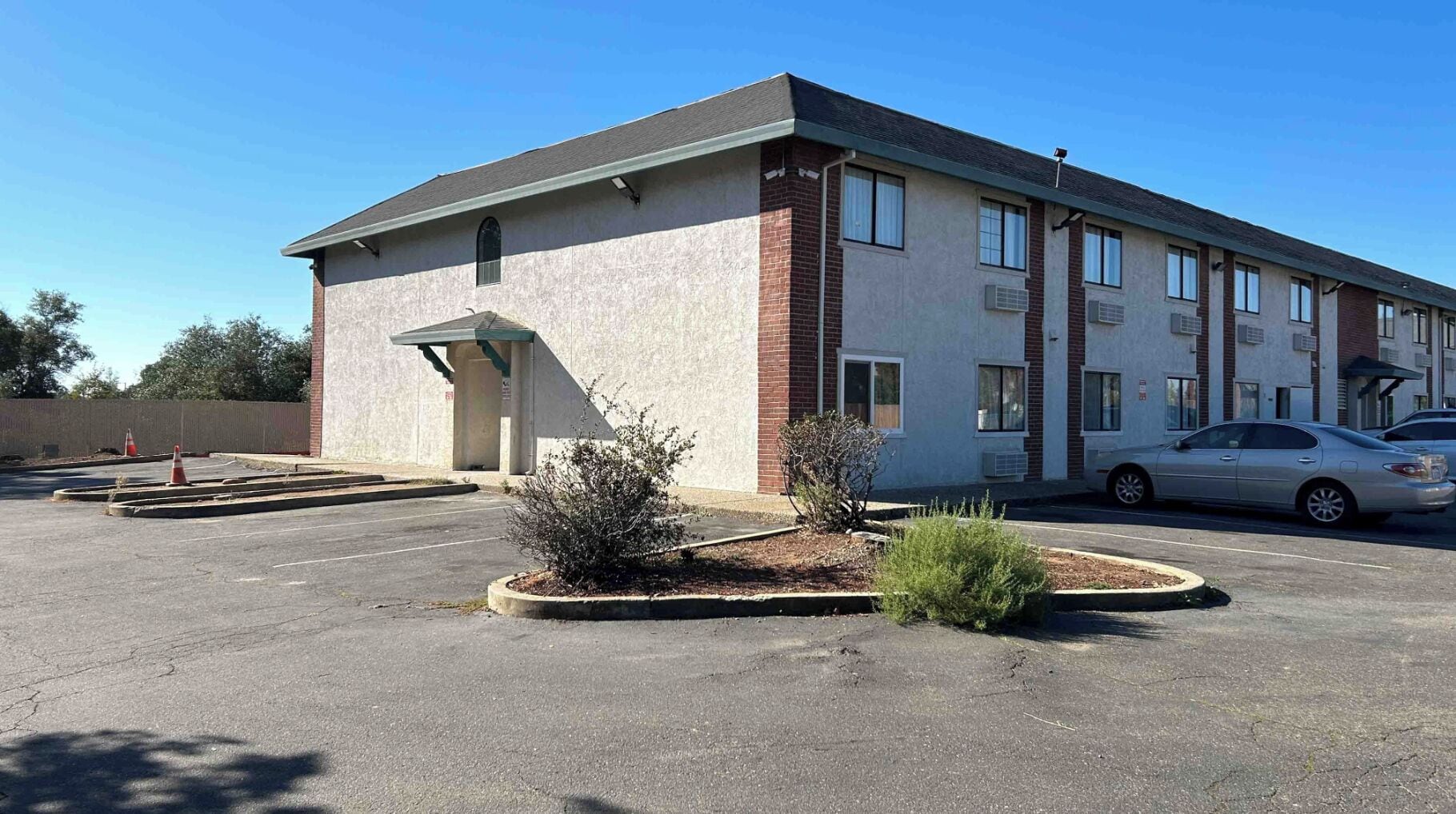 A building with a parking lot, a covered entrance, and a car parked in front.