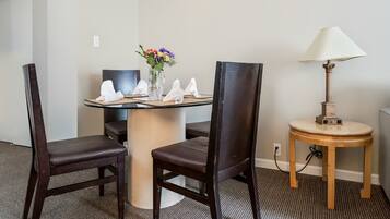 Hotelkamer met een ronde tafel, twee stoelen, een vaas met bloemen, een lamp en een vloerbedekking.