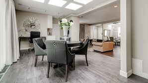 Un salon moderne avec un coin repas, agrémenté d’une lucarne, d’un miroir rond et d’un vase de fleurs.