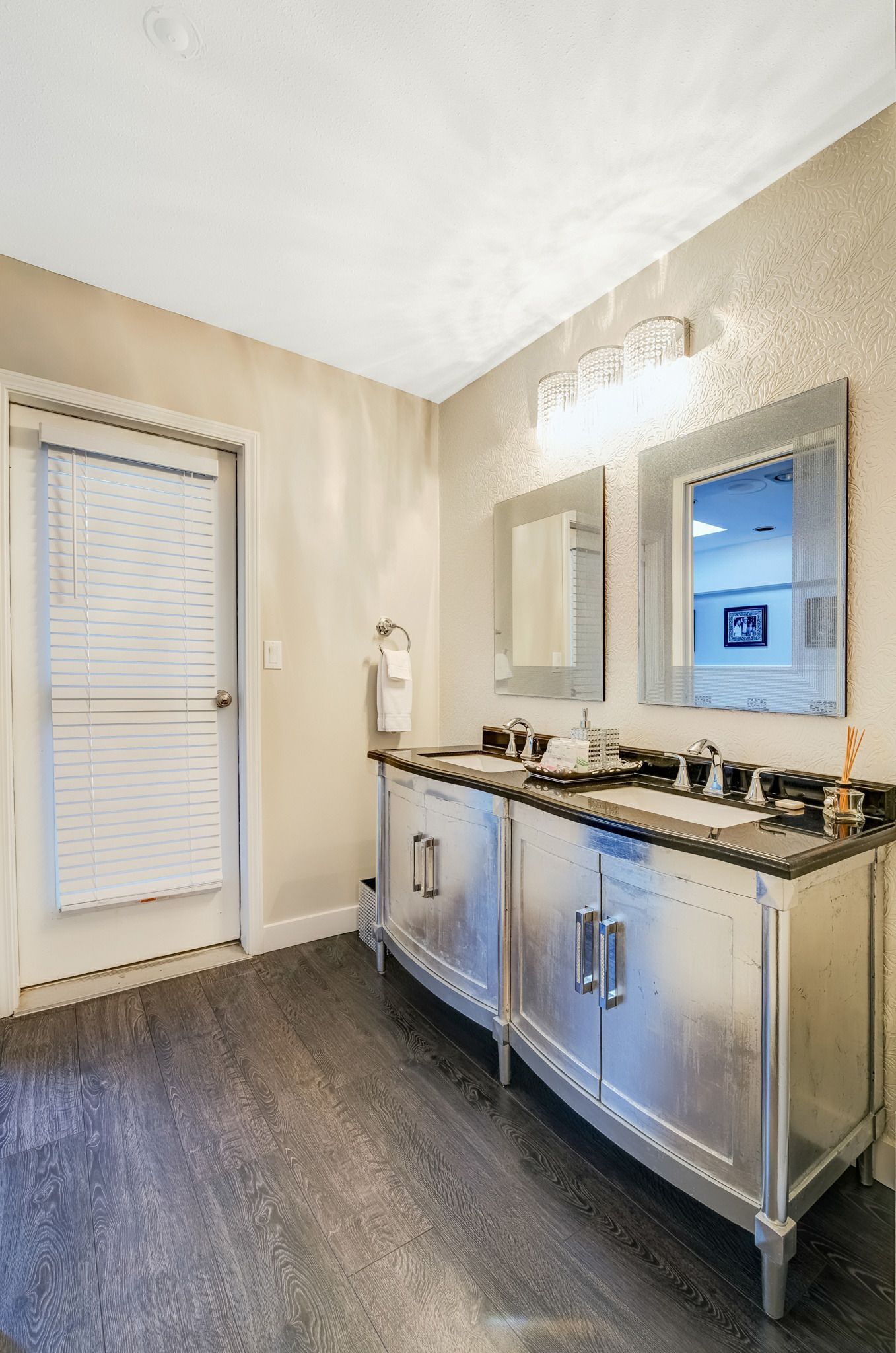 A bathroom with a double sink vanity, a towel rack, and a mirror with a picture frame.