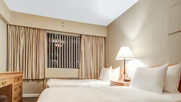 Habitación de hotel con una cama grande, un escritorio, una lámpara y una ventana con cortinas.