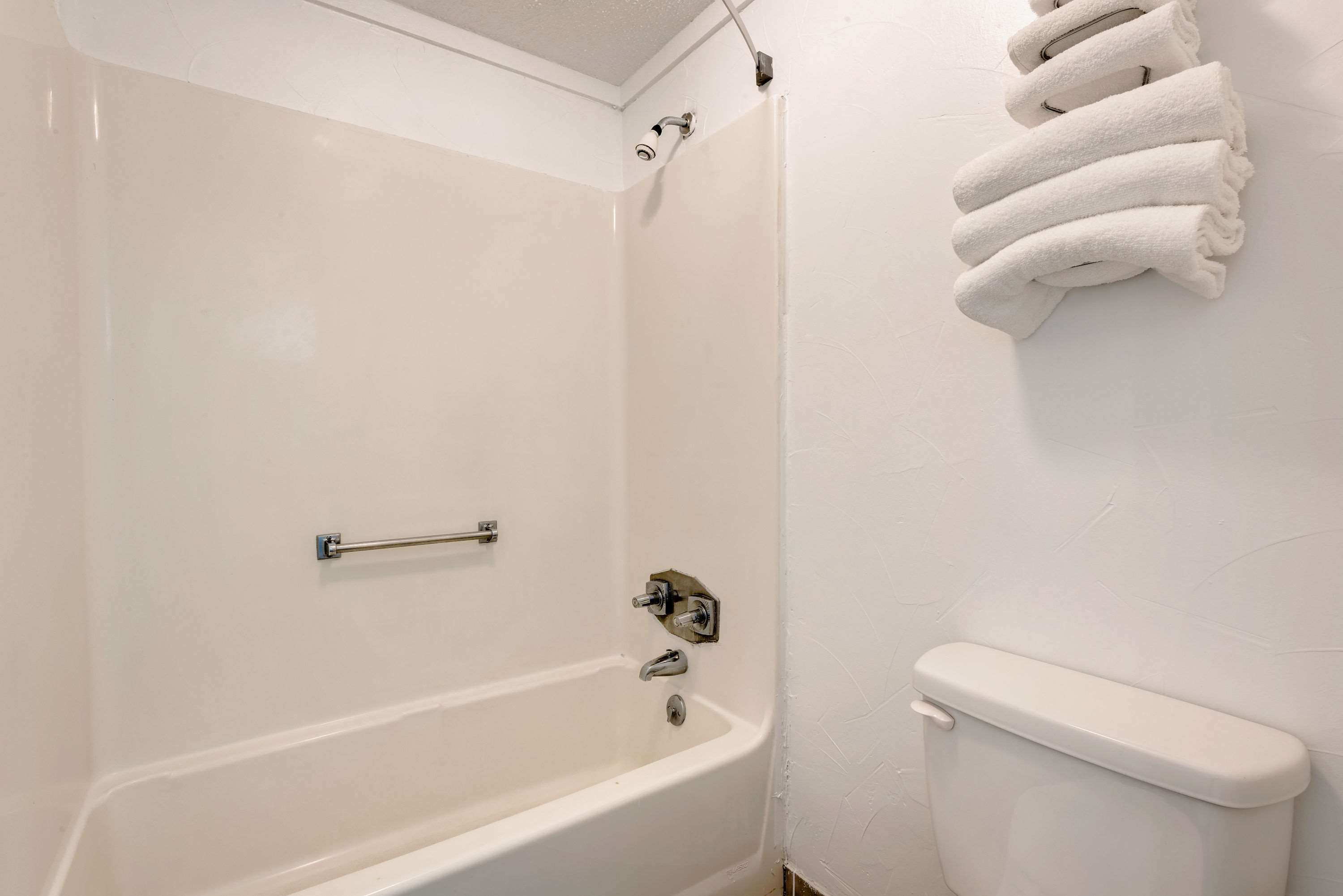 A bathroom with a white bathtub, a toilet, and a towel rack with folded towels.