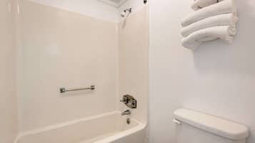 Un baño con una bañera blanca, un inodoro y un perchero con toallas dobladas.