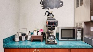 A kitchen with a coffee maker, microwave, and various kitchen utensils on the counter. - Knights Inn Macedonia (Macedonia)