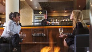 A bar area with a fire feature, seating, and a bar counter with bottles. - Hotel Grand Chancellor Launceston (Launceston)