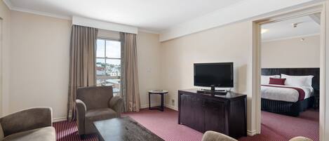 A hotel room with a large bed, a TV, a desk, and a sofa.