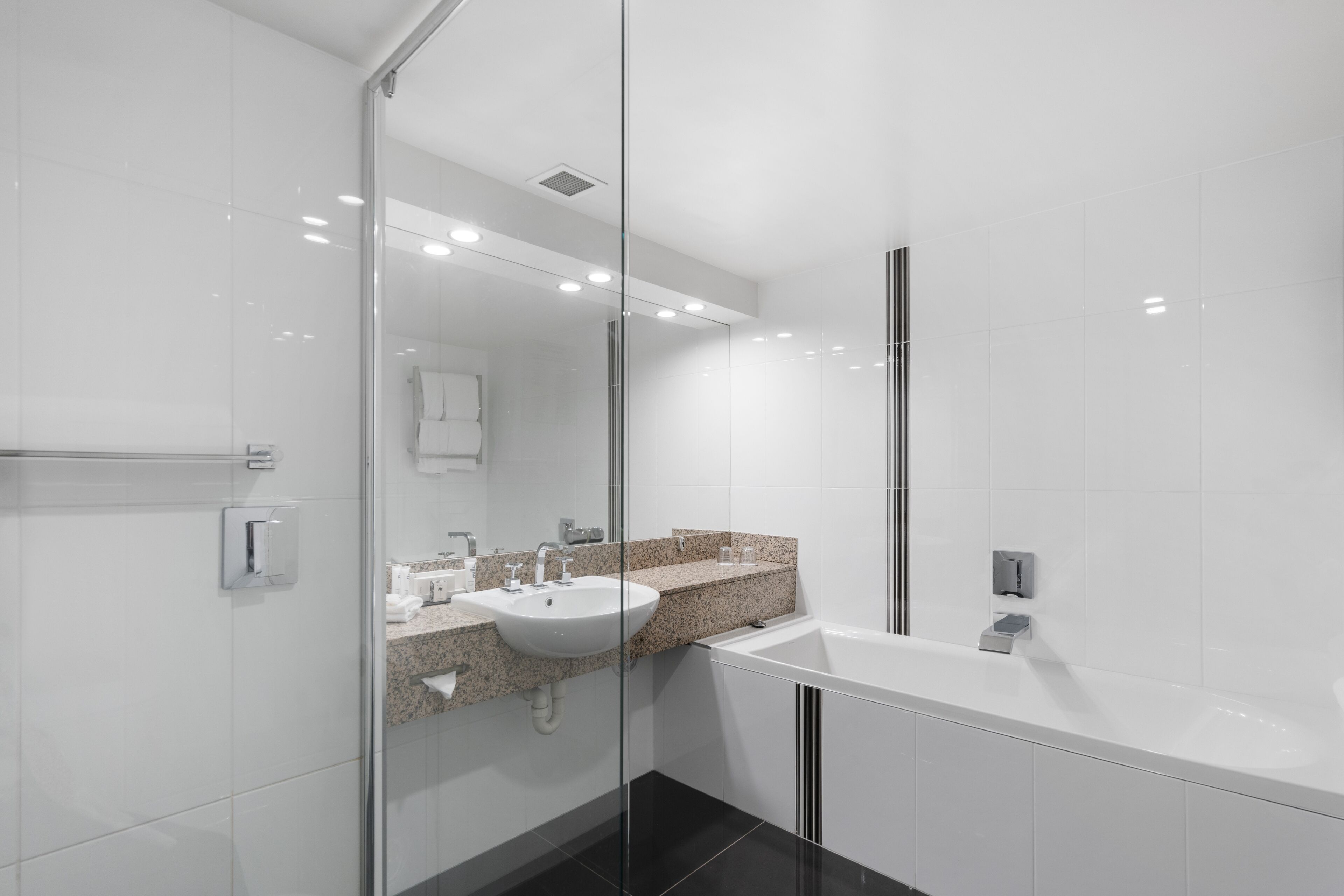 A modern bathroom with a glass shower enclosure, a white sink, and a large bathtub.