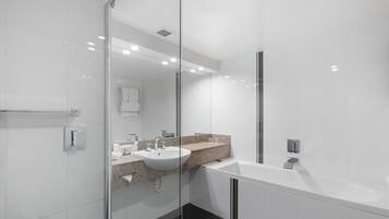 A modern bathroom with a glass shower enclosure, a white sink, and a large bathtub.