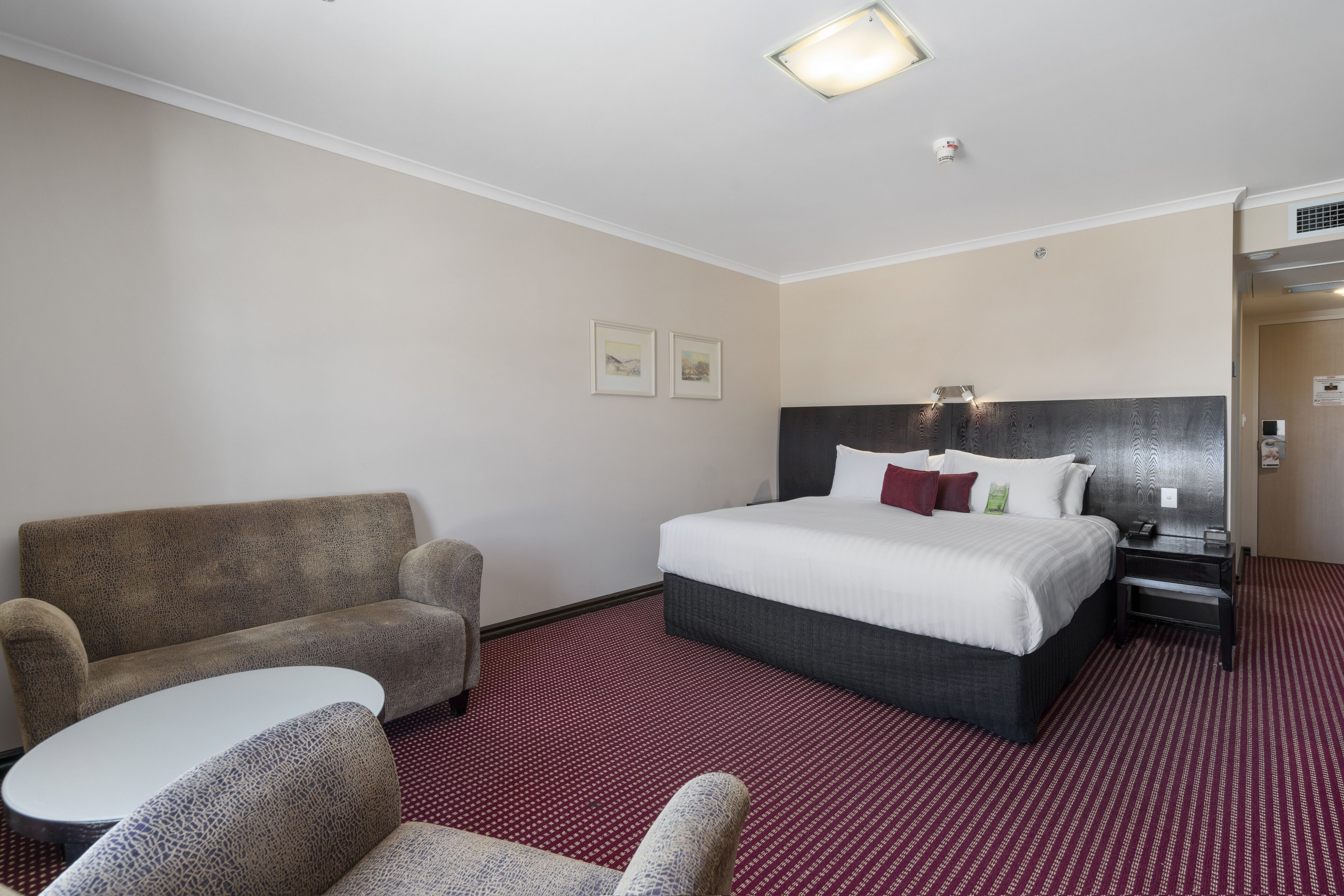 Una habitación de hotel con una cama grande, un sofá, una mesita y una mesilla de noche.