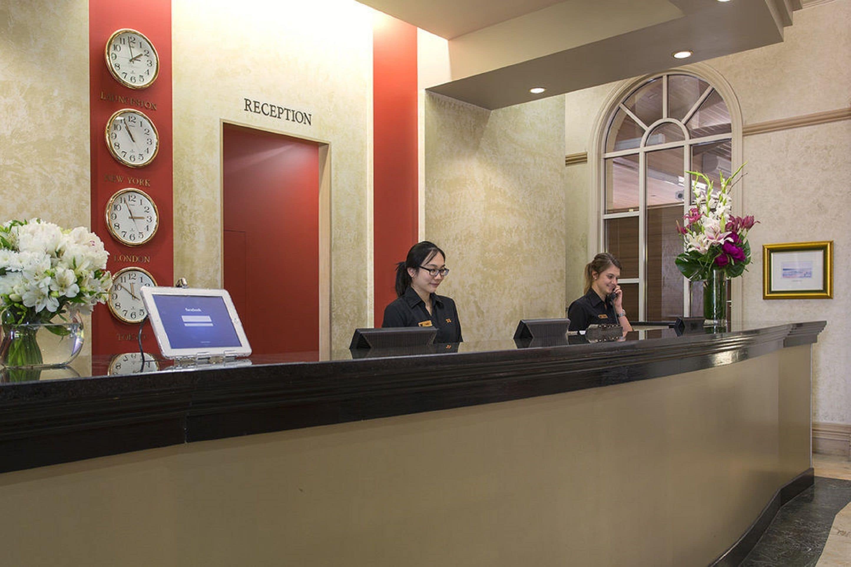 A reception desk with clocks indicating different time zones, a reception sign, and a framed picture on the wall.