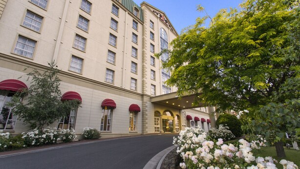 A hotel with a large entrance, multiple windows, and a well-maintained garden with white flowers. - Hotel Grand Chancellor Launceston (Launceston)