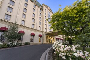 A hotel with a large entrance, multiple windows, and a well-maintained garden with white flowers. - Hotel Grand Chancellor Launceston (Launceston)