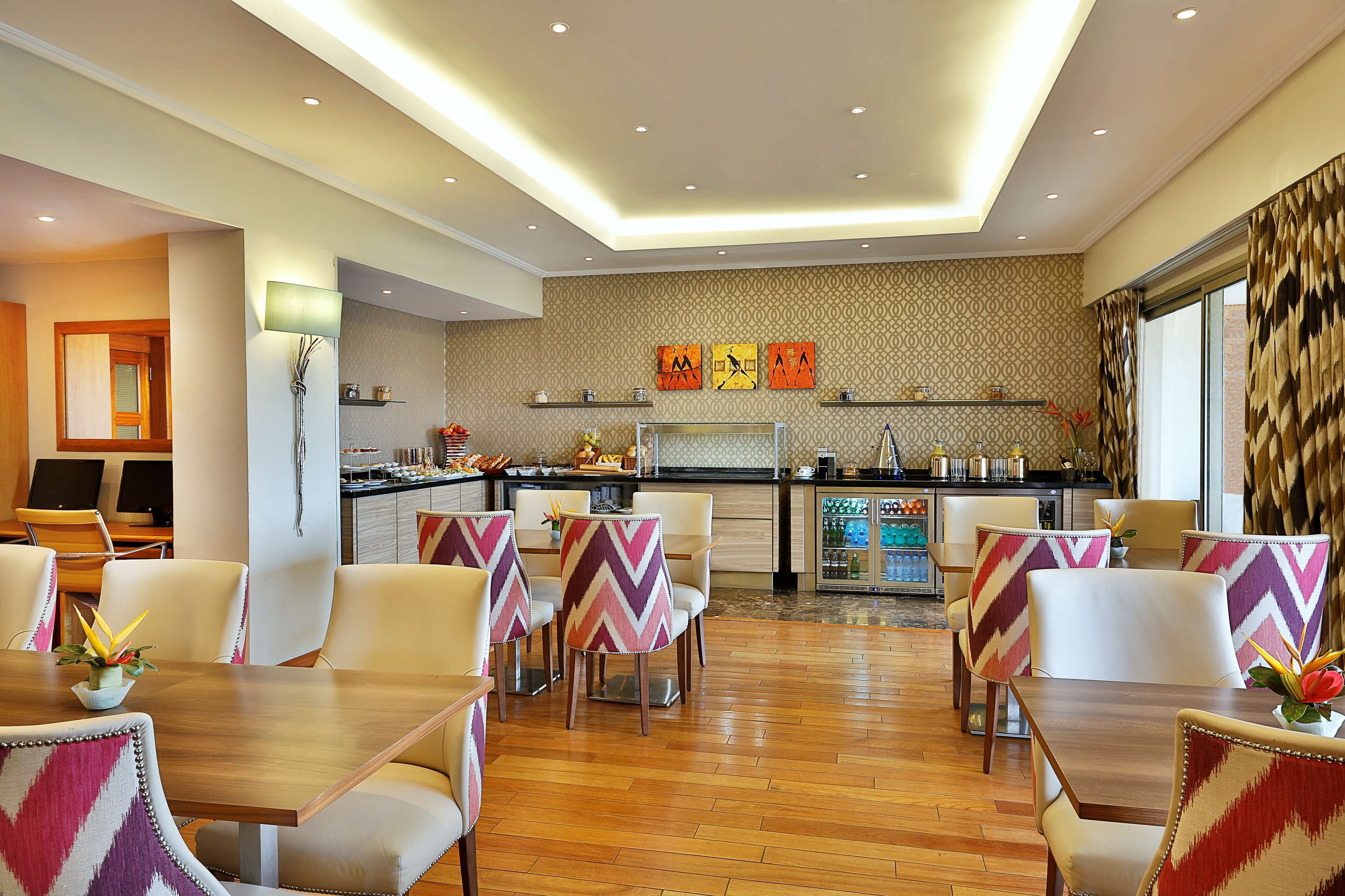 Un espace de restauration d’hôtel doté d’une cuisine centrale, d’un décor moderne et offrant une vue sur la ville.