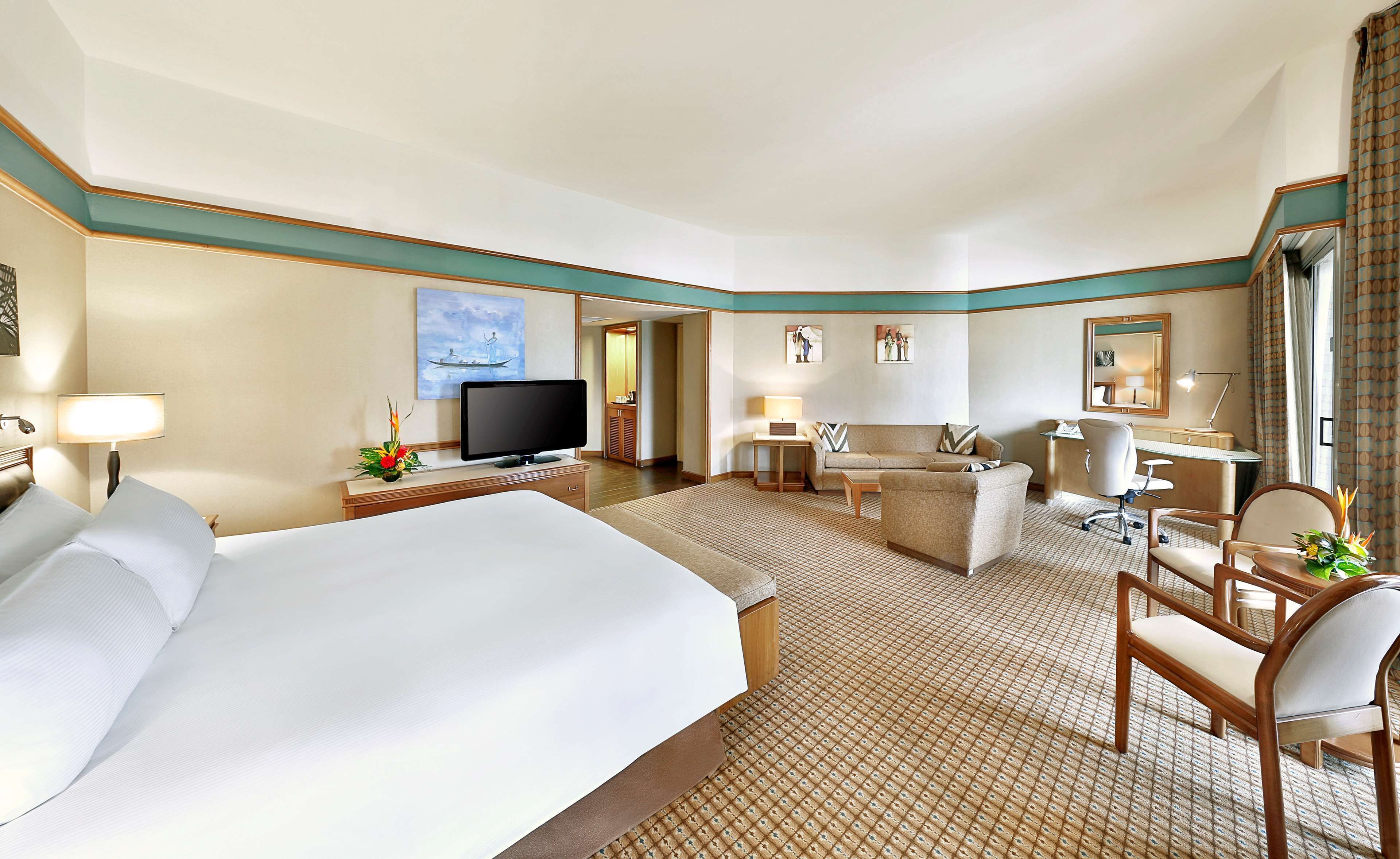 Habitación de hotel con una cama grande, un escritorio con computadora, un sofá, una silla y una mesita.
