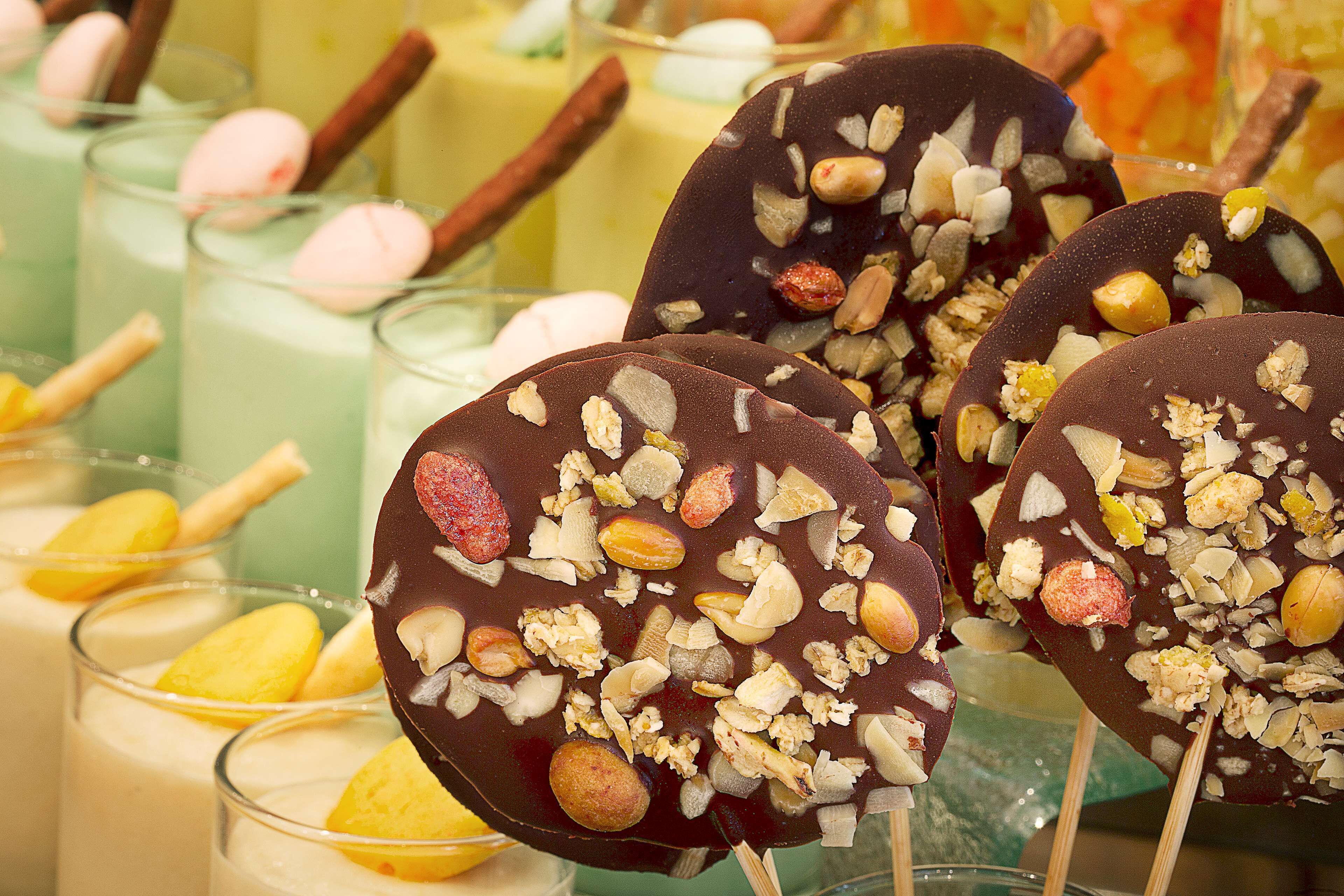 A selection of desserts including chocolate-covered treats with nuts and a variety of colorful beverages.