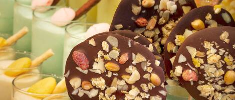 A selection of desserts including chocolate-covered treats with nuts and a variety of colorful beverages.