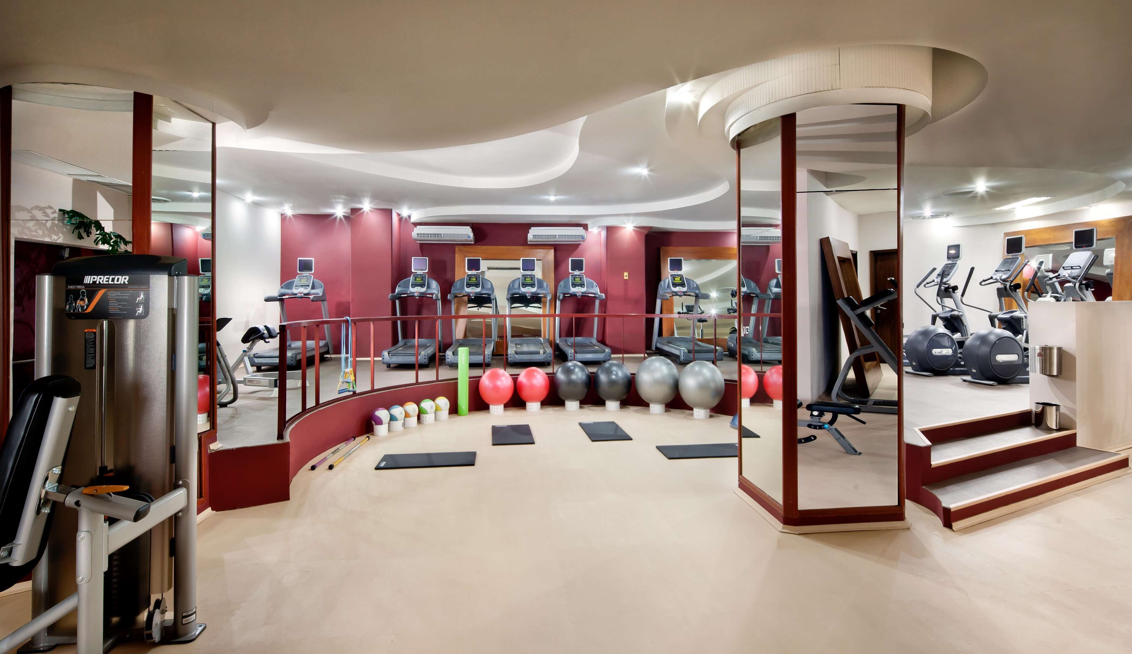 Un gimnasio moderno con máquinas de cardio, equipo de levantamiento de pesas y pelotas de ejercicio.