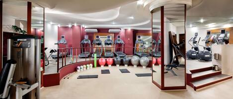 Un gimnasio moderno con máquinas de cardio, equipo de levantamiento de pesas y pelotas de ejercicio.