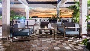 Un espace extérieur aménagé avec des sièges, un sol à carreaux, des canapés et une table.