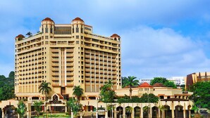 Un grand hôtel à plusieurs étages, doté d’une cour intérieure et entouré de palmiers.