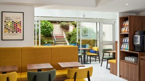 Um interior moderno com assentos amarelos, uma escadaria que leva a um jardim, e um cartaz Bauhaus emoldurado.